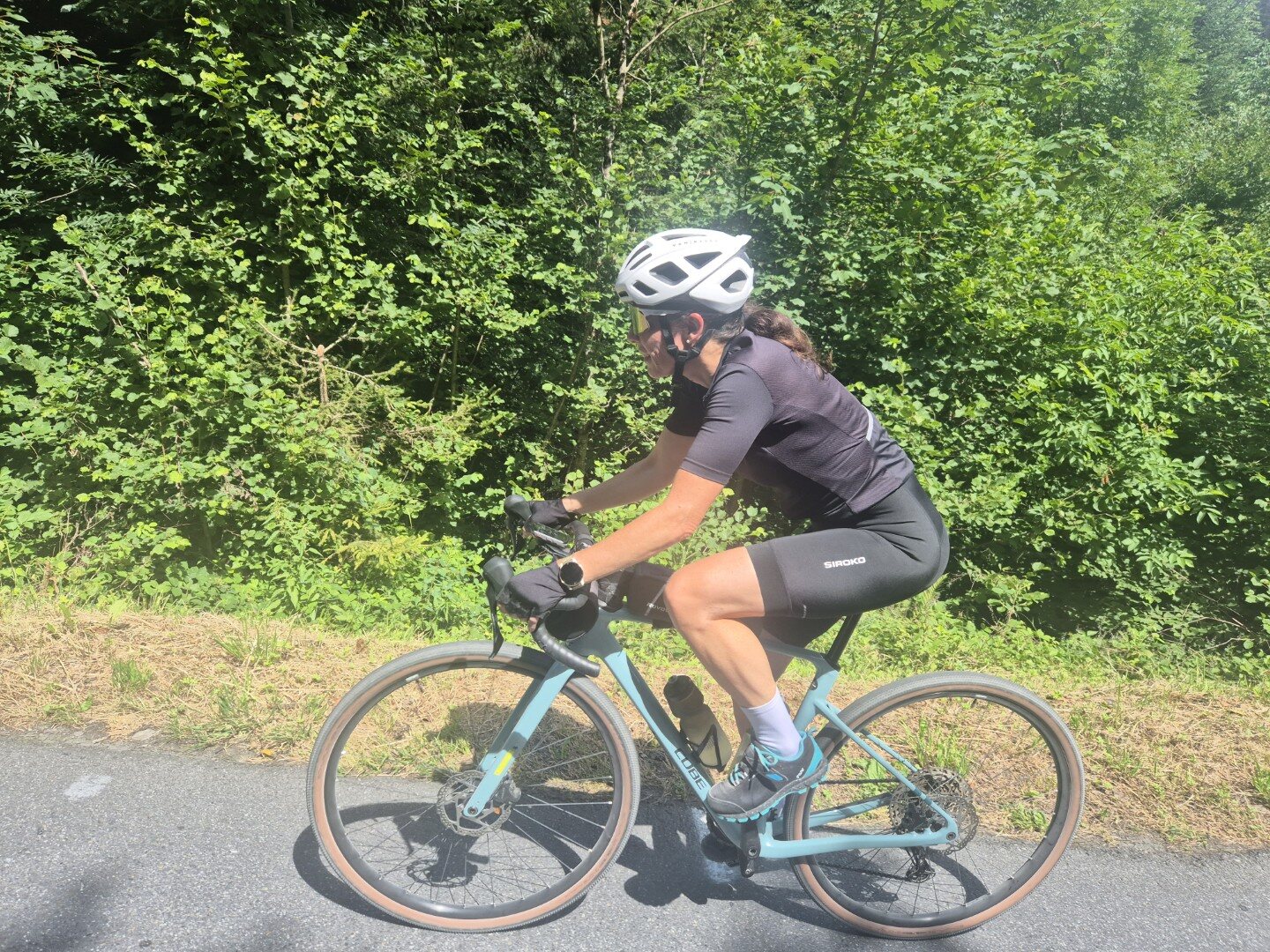 Cyclist riding through a sunlit green landscape